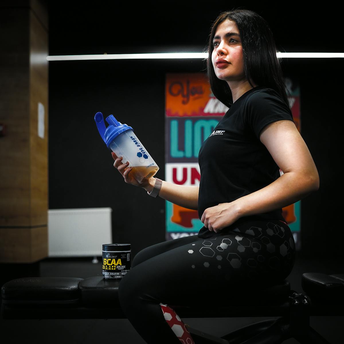 Fitness enthusiast in sportswear holding a shaker bottle indoors at Sulaymaniyah gym.